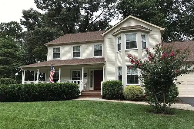 White colonial home with new roof and front porch